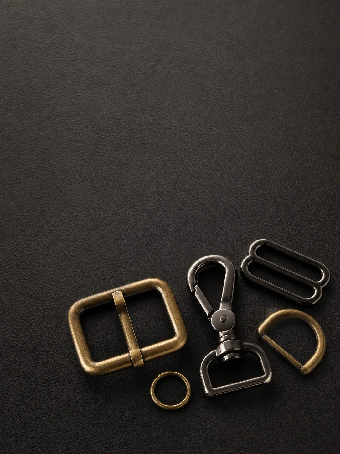 Photorealistic dark leather product catalog cover with brass and gunmetal bag hardware samples